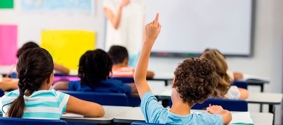 Enfant levant le doigt en classe
